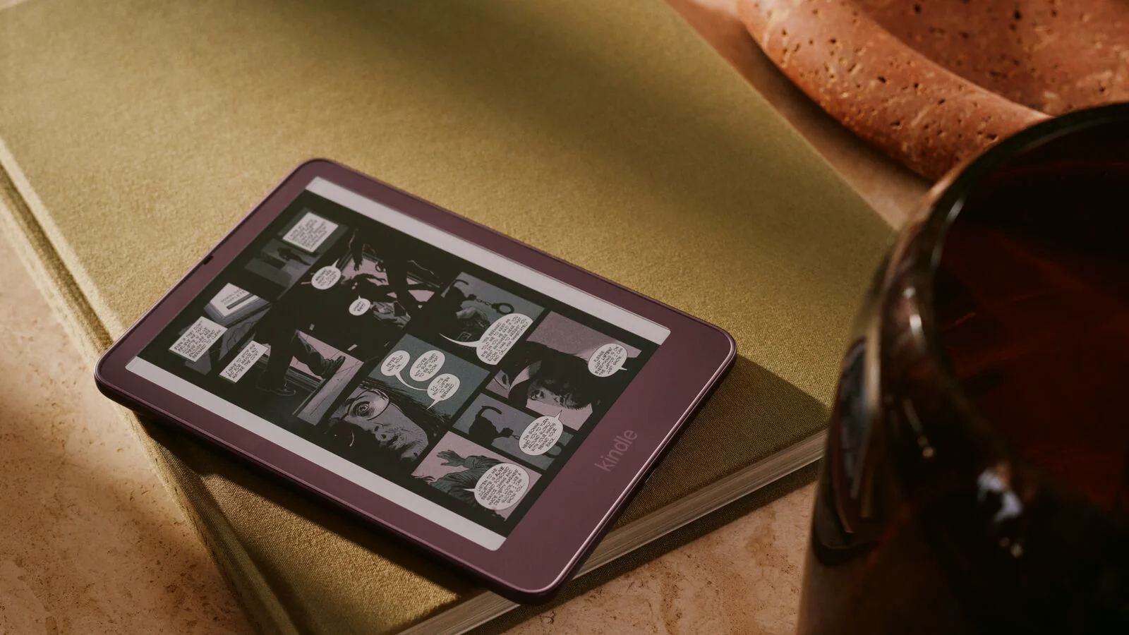 Kindle Colorsoft Signature Edition de 2026 en color granate, con una página de cómic en pantalla, sobre un cuaderno verde
